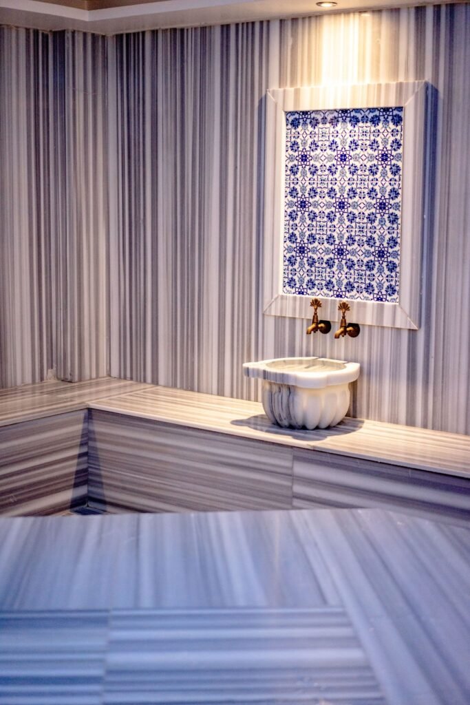 Interior of a traditional Turkish hamam featuring marble and mosaic tiles with brass faucets